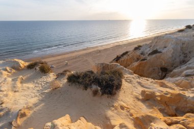 Günbatımında el değmemiş Arenosillo plajının yüksek açılı manzarası, Mazagon, Huelva, İspanya 'daki dramatik kumtaşı kayalıkları ve Atlantik kıyı şeridi.