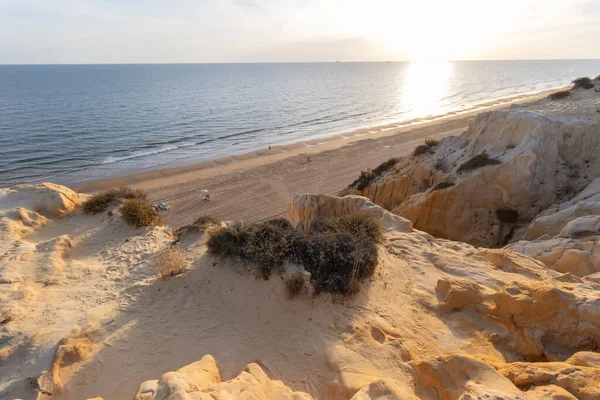 High-angle scenic view of the pristine Arenosillo beach at sunset, featuring dramatic sandstone cliffs and the Atlantic coastline in Mazagon, Huelva, Spain.