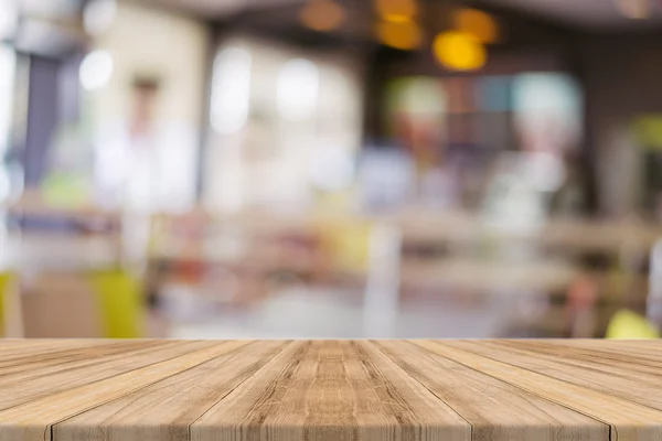 Träskiva tomma bord framför suddig bakgrund. Perspektiv brunt trä över oskärpa i restaurang - kan användas för visning eller montage dina produkter. Håna upp för visning av produkten. — Stockfoto