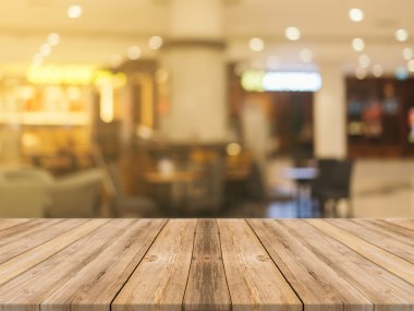 Tahta masa bulanık arkaplanın önünde boş. Kahve dükkanında görüntünün üzerindeki perspektif kahverengi ahşap ürünlerinizi sergilemek ya da montajlamak için kullanılabilir. Ürün gösterimi için modelleyin.