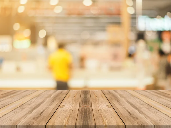 Ξύλινη σανίδα άδειο τραπέζι μπροστά από θολή φόντο. Προοπτική καφέ ξύλο πάνω από θαμπάδα στην καφετέρια - μπορεί να χρησιμοποιηθεί για επίδειξη ή μοντάζ τα προϊόντα σας.. — Φωτογραφία Αρχείου