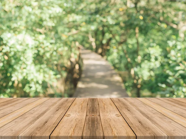 Holzbrett leerer Tisch vor verschwommenem Hintergrund. Perspektive braunes Holz über verschwommene Bäume im Wald - kann als Attrappe zur Anzeige oder Montage Ihrer Produkte verwendet werden. Frühlingszeit. Jahrgang gefiltert. — Stockfoto