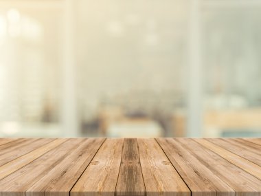Tahta masa bulanık arkaplanın önünde boş. Kahve dükkanında görüntünün üzerindeki perspektif kahverengi ahşap ürünlerinizi sergilemek ya da montajlamak için kullanılabilir. Ürün gösterimi için modelleyin.