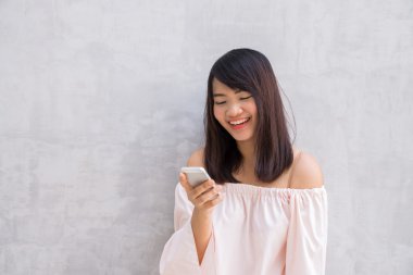 Beton duvardan istimal cellphone, güzel Asyalı kadın