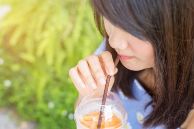 içecekler, insanlar ve yaşam tarzı kavramı - yakın bir kafede saman ile plastik bardak buzlu çay içme kadın