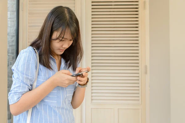 Kvinne skriver SMS på smarttelefon på en kafe. Bildet av en ung kvinne som sitter ved et bord med en kaffe ved hjelp av mobiltelefon. – stockfoto