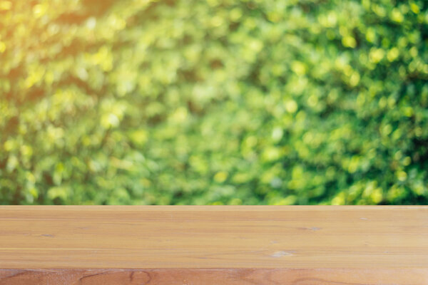 Wooden board empty table in front of blurred background. Perspective brown wood over blur trees in forest - can be used for display or montage your products. spring season. vintage filtered image.