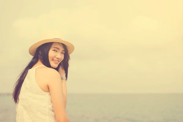 Outdoor summer portrait of young pretty woman looking to the ocean at tropical beach, enjoy her freedom and fresh air, wearing stylish hat and clothes, Vintage filtered image. — Stock Photo, Image