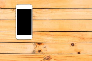 Üstten Görünüm smartphone şablon boşaltmak ile ahşap masa üstünde siyah perde ile alay etmek.