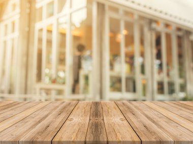 Tahta masa bulanık arkaplanın önünde boş. Kahve dükkanında görüntünün üzerindeki perspektif kahverengi ahşap ürünlerinizi sergilemek ya da montajlamak için kullanılabilir. Ürün gösterimi için modelleyin.