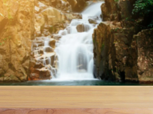 Tablero de madera mesa vacía en frente de fondo borroso. Perspectiva de madera marrón sobre la cascada borrosa en el bosque - se puede utilizar para mostrar o montar maqueta de sus productos. vintage imagen filtrada . — Foto de Stock