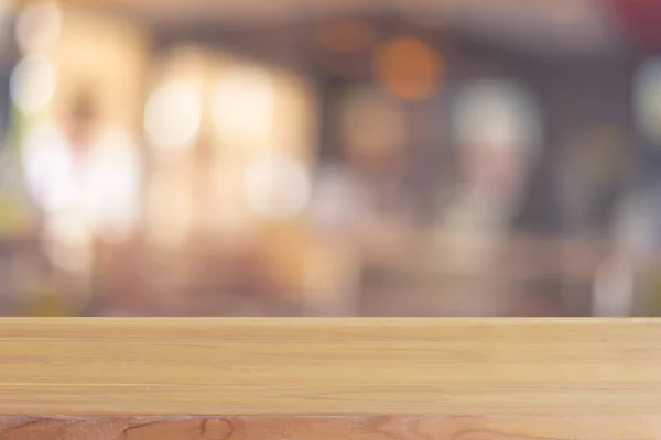 Träskiva tomma bord framför suddig bakgrund. Perspektiv brunt trä över oskärpa i kafé - kan användas för visning eller montage håna upp dina produkter. Vintage filtrerade bilden. — Stockfoto