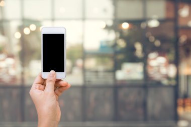 Arka planda akıllı telefonla alışveriş online kavramı alışveriş alışveriş merkezi, akıllı telefon üzerinde elinde beyaz ekran ile bulanık