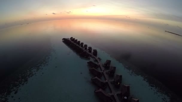 Luchtfoto van de zonsondergang over de zee en de luxe overwater villa's op tropisch eiland resort, Maldiven. — Stockvideo