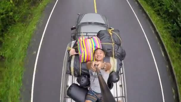 車の屋根の上の男 selfie が道を走っていた. — ストック動画