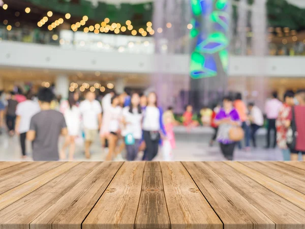 Placa de madeira mesa vazia na frente do fundo borrado. Perspectiva de madeira marrom sobre pessoas desfocadas em shopping center - pode ser usado para exibição ou simular montagem de seus produtos . — Fotografia de Stock
