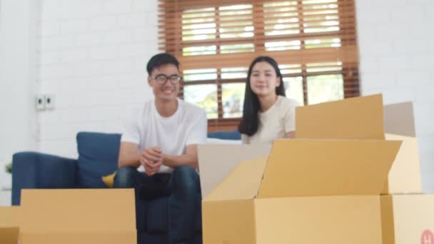 兴高采烈的亚洲年轻人买到了新房子 韩国妈妈 爸爸和女儿一起在新家拆包的过程中玩耍 搬家后一起坐在地板上和箱子在一起 — 图库视频影像