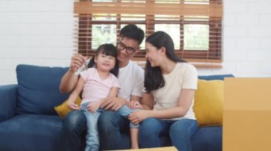 Mutlu Asyalı genç bir ailenin portresi yeni bir ev aldı. Anne ve babası olan Japon bir anaokulu kızı. Oturma odasındaki kanepede oturmuş kameraya bakıp gülümsüyor..