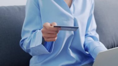Dizüstü bilgisayar, kredi kartı ve e-ticaret interneti kullanan genç bir Asyalı kadın. Evdeki oturma odasında. Evde kal, online alışveriş, kişisel izolasyon, sosyal uzaklık, koronavirüs için karantina.