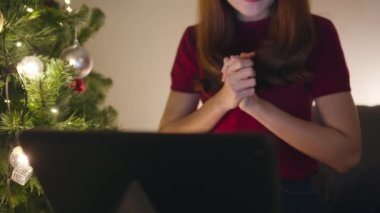 Genç Asya 'lı kadın, X' Mas hediye kutusuyla konuşan bir çiftle tablet görüntüsü kullanıyor. Evdeki oturma odasında süslerle süslenmiş bir Noel ağacı. Noel gecesi ve yeni yıl bayramı festivali.