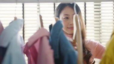 Güzel, çekici, genç Asyalı bayan moda kıyafetlerini evde ya da dükkanda seçiyor. Kız ne giyeceğini düşünüyor. Evde gardırop ya da giyim mağazası soyunma odası.