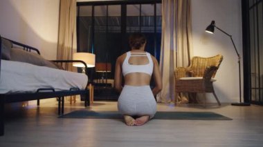 Spor kıyafetli genç Asyalı bayan geceleri oturma odasında yoga egzersizi yapıyor. Spor ve eğlence aktivitesi, sosyal uzaklık, korona virüsü önleme konsepti için karantina.
