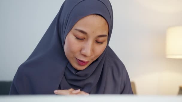 亚洲的穆斯林女士带着头巾 在家里晚上的客厅里远程工作时 用电脑笔记本电脑和同事谈论视频电话会议的计划 社会疏离 电晕病毒的检疫 — 图库视频影像