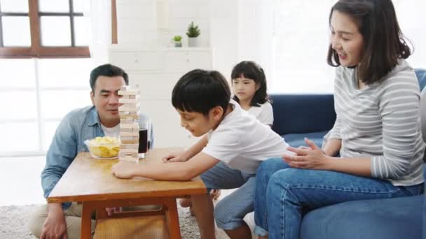 自宅のリビングルームでソファソファで木製の塔と楽しいボードゲームの趣味を持つ幸せな陽気なアジアの家族 一緒に過ごす時間 社会的距離 コロナウイルスの予防のための隔離 — ストック動画