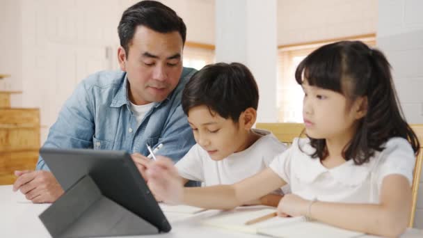 幸せなアジアの家族のホームスクーリング 父は自宅のリビングルームでデジタルタブレットを使用して子供たちを教えています 一緒に過ごす時間 自己分離 社会的距離 コロナウイルスの予防のための隔離 — ストック動画