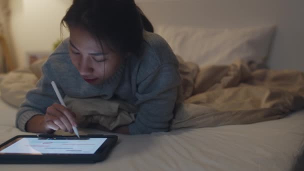 家の夜に寝室のベッドの上でタブレットを使用してフリーランスのアジアの女性のカジュアルウェアの肖像画 自宅からの作業 遠隔作業 社会的距離 コロナウイルスの予防のための隔離 — ストック動画