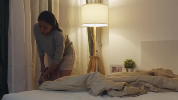 若いアジア人女性が家の寝室でベッドを掃除している 美しいインドの女性は 夜寝る前にベッド毛布を作りました 時間洗浄ホームコンセプトを使用してライフスタイルの女性 — ストック動画
