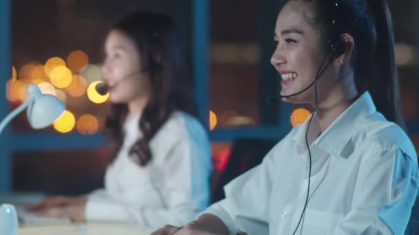 千年亚洲青年呼叫中心团队或客户服务主管在深夜办公室使用电脑和麦克风耳机提供工作技术支持 电话推销或销售工作概念 — 图库视频影像