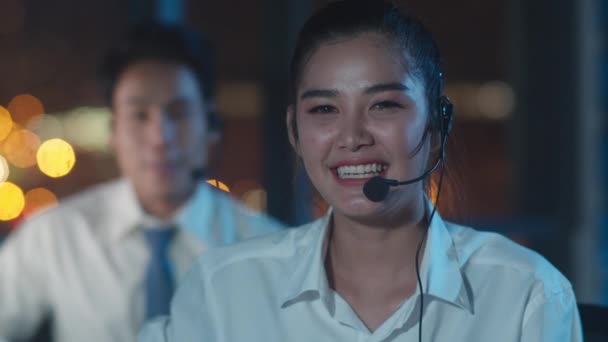 千年亚洲青年呼叫中心团队或客户服务主管在深夜办公室使用电脑和麦克风耳机提供工作技术支持 电话推销或销售工作概念 — 图库视频影像