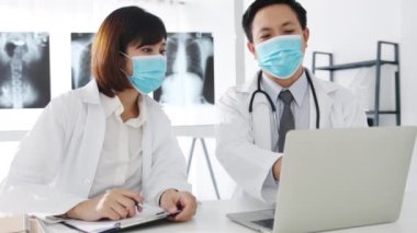 Asya 'nın tıbbi ekibi ciddi bir erkek ve genç bayan doktor koruyucu maskeli bilgisayarlı tomografiyi tartıştılar ve hastane ofisinde sonuçlandı. Sosyal mesafe, Corona virüsünden sonra yaşam tarzı yeni normal.