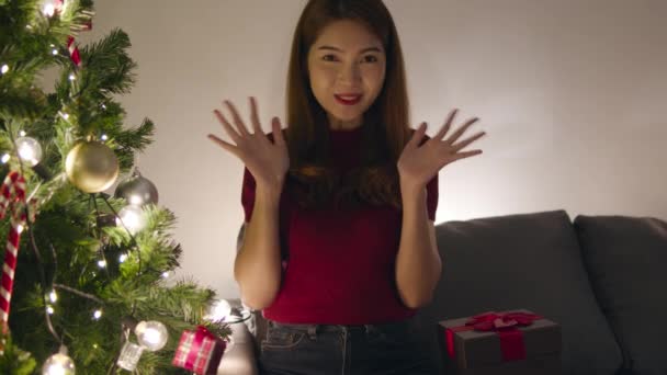 若いアジアの女性のVloggerは 家庭でのリビングルームで装飾で飾られたカップル クリスマスツリーとのカメラのビデオ通話の話を見てください 社会的な距離 クリスマスの夜と新年の休日の祭り — ストック動画