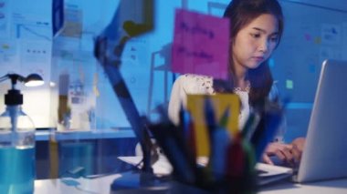 Serbest çalışan Asyalı kadınlar yeni normal ofis bilgisayarlarında çok çalışıyorlar. Geceleri ev aşırı yükleme, uzaktan çalışma, kişisel izolasyon, sosyal uzaklık, korona virüsünün önlenmesi için karantina.