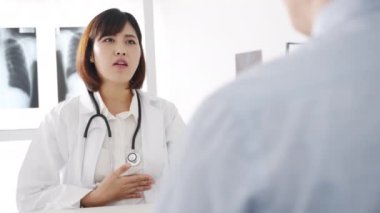 Bilgisayarlı beyaz üniformalı genç Asyalı kadın doktor harika haberler sunuyor. Sonuçları ya da belirtileri erkek hastalarla tartışıyor. Sağlık kliniğinde ya da hastane ofisinde masada oturuyor..