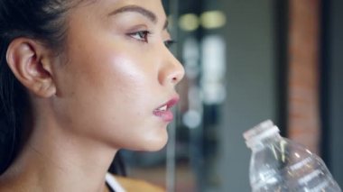 Güzel genç Asyalı bayan spor salonunda yağ yakma egzersizinden sonra su içiyor. Altılı paketli sporcu, sportif kadın aktivitesi, fonksiyonel eğitim, sağlıklı yaşam tarzı konsepti.