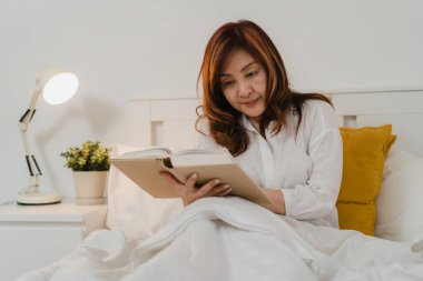 Asyalı yaşlı kadınlar evde dinlenir. Asya 'nın son sınıf Çinli dişileri, gece konseptinde yatak odasında uzanıp kitap okurken dinlenmenin keyfini çıkarıyorlar..