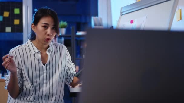 アジアのビジネスマン女性の社会的距離は オフィスの夜の仕事中にビデオ通話で計画について同僚にカメラのプレゼンテーションを見てウイルスの予防のための新しい通常で コロナウイルス後の生活様式 — ストック動画