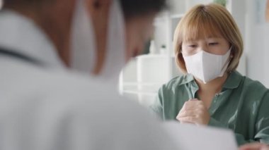 Genç Asyalı doktor, pano kullanarak koruyucu maske takıyor. Haberler sunuyor. Sonuçları ya da belirtileri hastanedeki kız hastayla tartışıyor. Corona virüsünden sonra yaşam tarzı yeni normal.