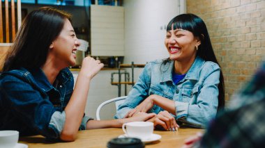 Bir grup mutlu Asyalı genç arkadaş kafeteryada birlikte otururken eğleniyor ve eğleniyorlar. Kahve dükkanı tatil aktivitesi, modern arkadaşlık yaşam tarzı konsepti..