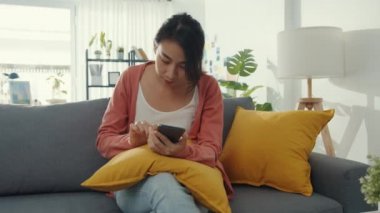 Kanepede oturan güzel Asyalı kadın harika haberlerle heyecan verici hissediyor. Başarı röportajı, mezuniyet başarısı, flört müsabakası kabul, başlangıç kredi onayı, sınavı, işveren iş teklifini kabul ediyor.