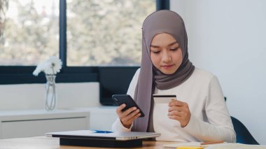 Asya 'daki Müslüman kadın telefon, kredi kartı satın alma ve e-ticaret interneti kullanıyor. Evde kal, online alışveriş, kişisel izolasyon, sosyal uzaklık, koronavirüs önleme için karantina.