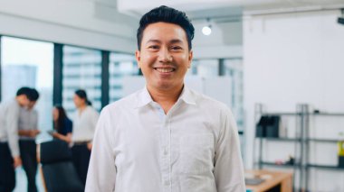 Başarılı yönetici iş adamının portresi. Modern ofis işyerinde kameraya bakıp gülümseyen şık giyimli. Genç Asyalı adam çağdaş toplantı odasında duruyor..