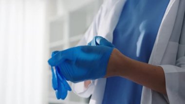 Genç Asyalı doktor ya da hemşire cerrahi ameliyata hazırlanıyor ve sağlık kliniğinde ya da hastane ofisinde eldiven takıyor. Sosyal uzaklık, koronavirüs için karantina.