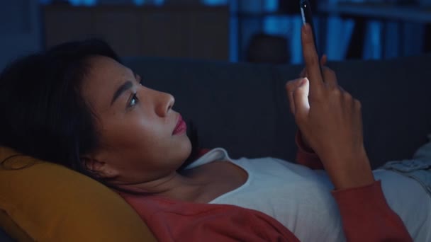 夜の中毒アジアの女性は 自宅でベッドの中でスマートフォンの睡眠を使用する退屈な感じとチェック電話をスクロールオンラインでメッセージを参照してください 自宅での滞在 自己隔離 インターネット中毒やモバイル虐待 — ストック動画