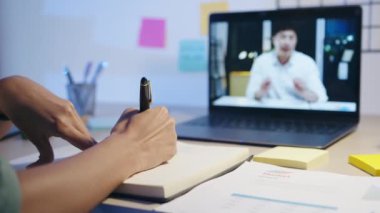 Dizüstü bilgisayar kullanan Asyalı iş kadını iş arkadaşlarıyla oturma odasındaki video görüşme planı hakkında konuşuyor. Geceleri ev aşırı yükleme, uzaktan çalışma, sosyal uzaklık, koronavirüs için karantina.