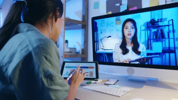 デスクトップトークを使用しているアジアのビジネスマンは リビングルームでのビデオ通話会議の計画について同僚に話します 夜間の家の過負荷から働く リモートワーク 社会的距離 コロナウイルスの隔離 — ストック動画