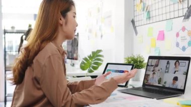 Dizüstü bilgisayar kullanan Asyalı işadamları iş arkadaşlarıyla yeni normal ofiste yapılacak video görüşmesi planlarını tartışıyor. Corona virüsünden sonra yaşam tarzı sosyal uzaklık ve çalışma.